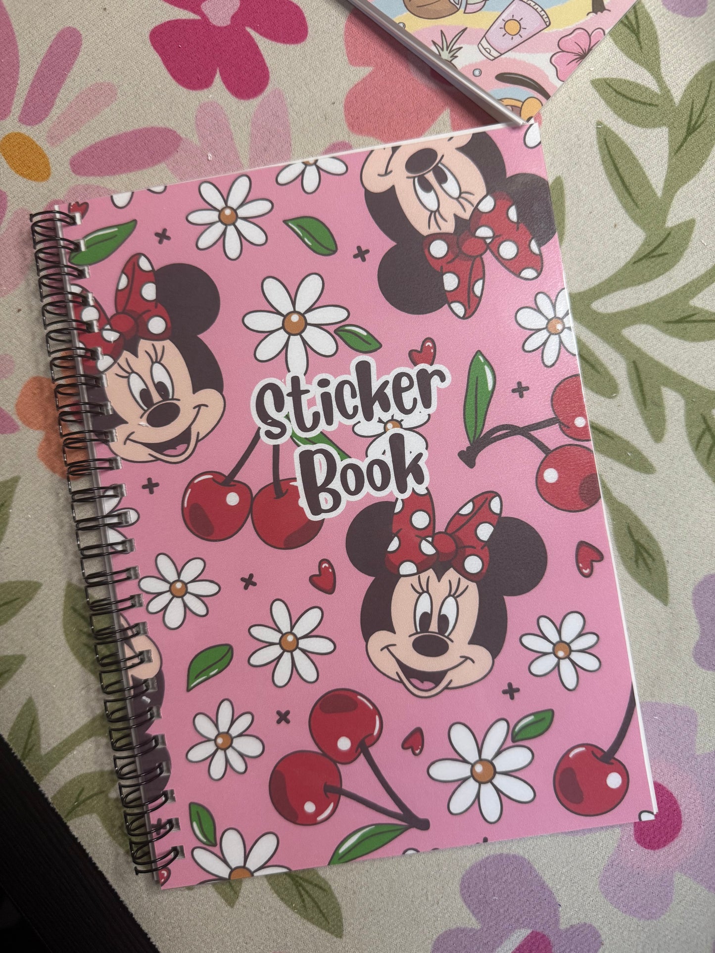 Pink sticker book with Minnie Mouse design on a floral-patterned surface
