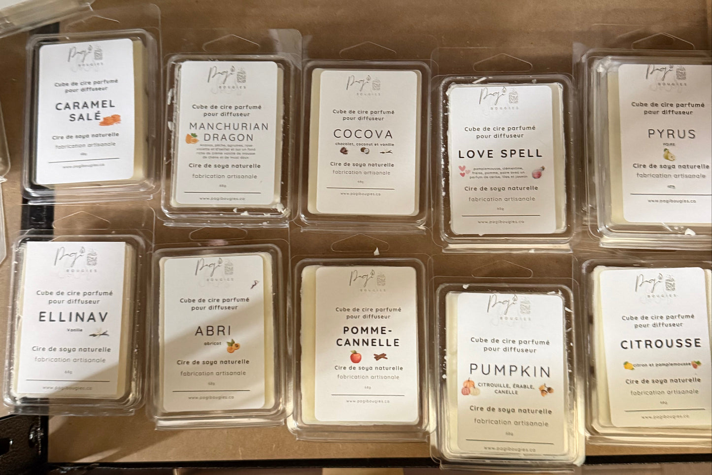 Packaged candles with labels on a cardboard surface