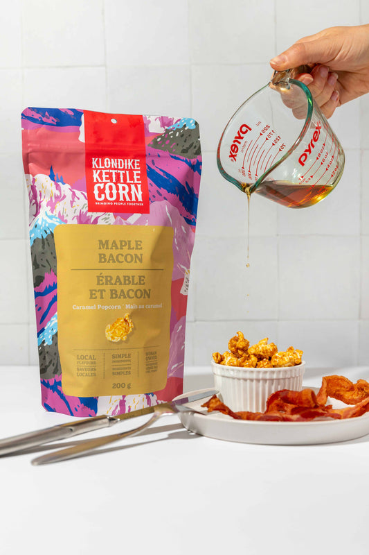 Klondike Kettle Corn Maple Bacon flavor packaging with a hand pouring oil over popcorn.